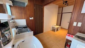 Una cocina compacta con un lavamanos, una mesita y un extintor.