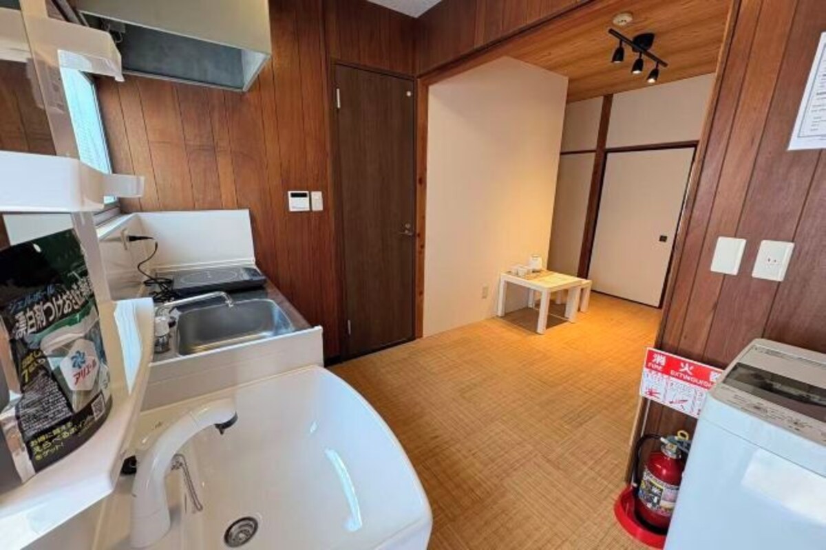 A compact kitchen with a sink, a small table, and a fire extinguisher.
