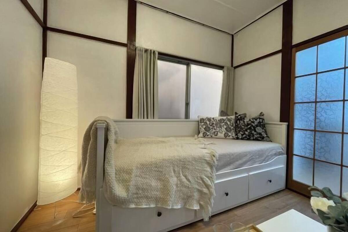 A bedroom with a bed, a window, and a curtain.