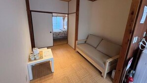 Una habitación con un sofá, una mesita con tazas, techo de madera y una puerta con extintor.