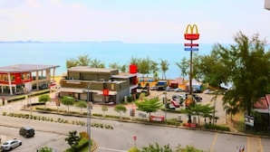 A McDonald's restaurant with a view of the sea, a parking lot, and a road with cars. - PD D'Wharf Premium Suite - Full Seaview (Up to 6 Pax) (Port Dickson)