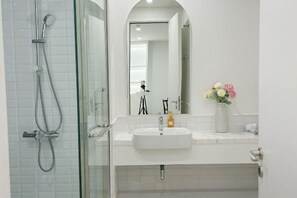 Une salle de bain moderne avec une douche à parois de verre, un lavabo blanc et un miroir au-dessus.