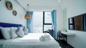Une chambre d’hôtel moderne équipée d’un lit, d’un bureau, d’une chaise et offrant une vue sur la plage.