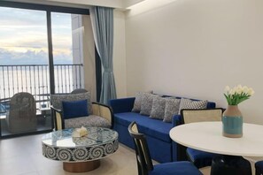 Een balkon met een bank, stoelen, een ronde salontafel en een vaas met bloemen.