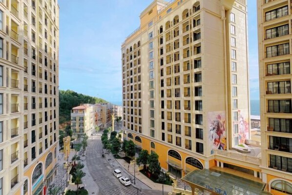 A multi-story hotel with a central courtyard, balconies, and a view of the street.