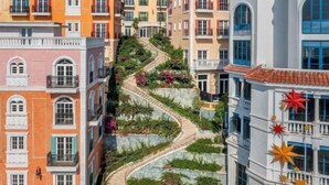 Un immeuble à plusieurs étages, avec un chemin sinueux reliant les différents niveaux, et entouré de verdure.