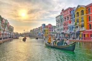 A canal with colorful buildings, a bridge, and a gondola with passengers. - Lalisa Hotel Grand World Phu Quoc (Phu Quoc)
