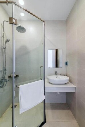 A modern bathroom with a glass-enclosed shower, a white sink, and a mirror above the sink. - Lalisa Hotel (Phu Quoc)