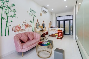 A reception area with a pink sofa, a round table, and a reception desk. - Lalisa Hotel (Phu Quoc)