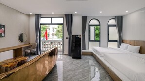 Ein Hotelzimmer mit Bett, Schreibtisch, Stuhl, Kühlschrank und Blick ins Freie.