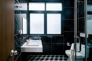 A bathroom with a white sink, a toilet, and a shower area. - Lalisa Hotel (Phu Quoc)