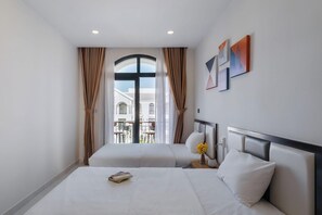 A hotel room with two beds, a balcony with a view, and artwork on the wall.