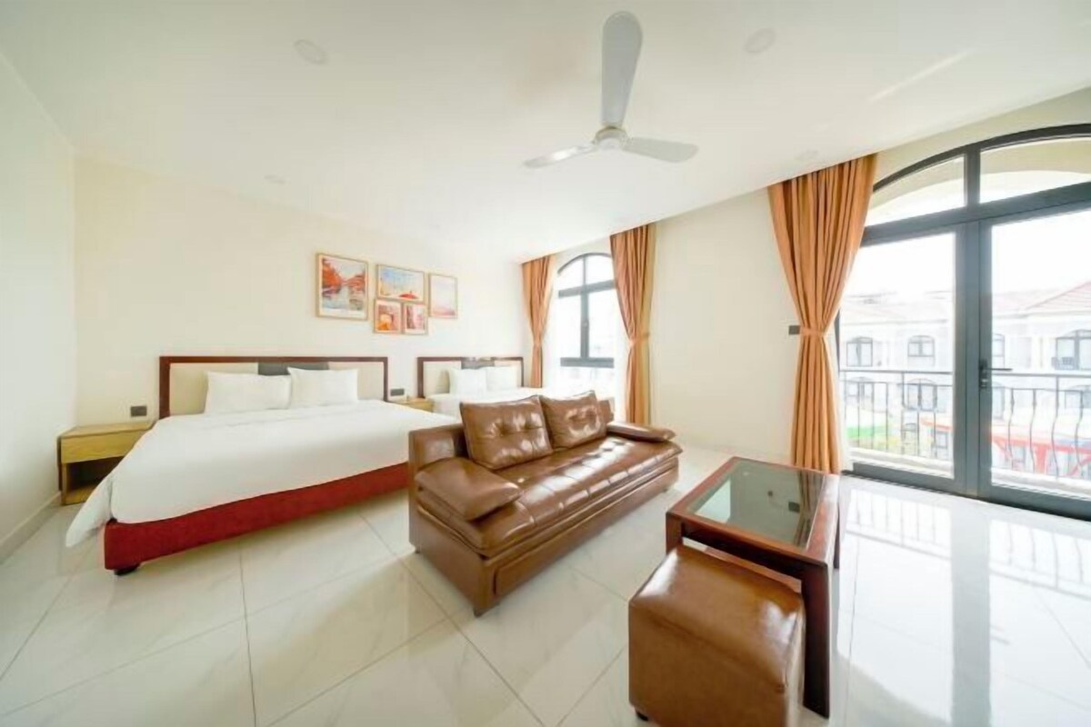 A hotel room with a bed, a sofa, a desk, and a large window.