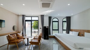 Ein Hotelzimmer mit einem Bett, einer Sitzecke mit Stühlen, einem Fernseher und einem großen Fenster.
