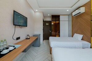 A hotel room with a TV, a desk with a kettle, a bed, and an air conditioning unit. - Lalisa Hotel (Phu Quoc)