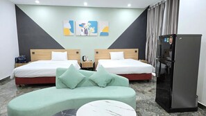 A hotel room with two beds, a sofa, a refrigerator, and artwork on the wall.