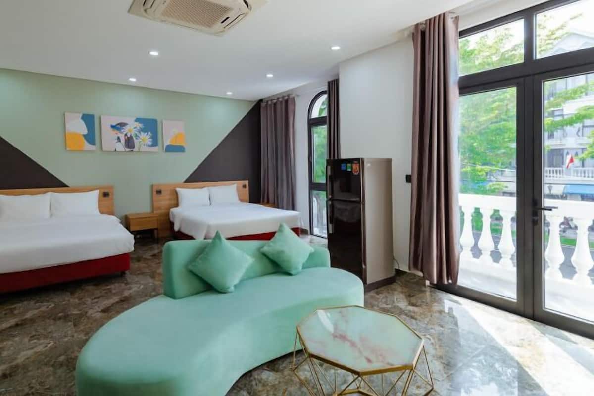 A hotel room with two beds, a sofa, a marble coffee table, and a balcony with a view.