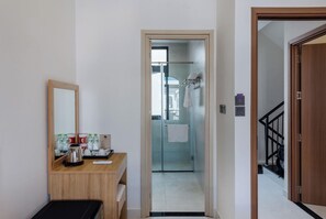 A hotel room with a wooden desk, a mirror, a coffee maker, and toiletries.