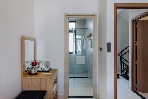 A hotel room with a wooden desk, a mirror, a coffee maker, and toiletries. - Lalisa Hotel (Phu Quoc)