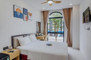 A hotel room with a bed, bedside table, nightstand, and a window with curtains. - Lalisa Hotel (Phu Quoc)