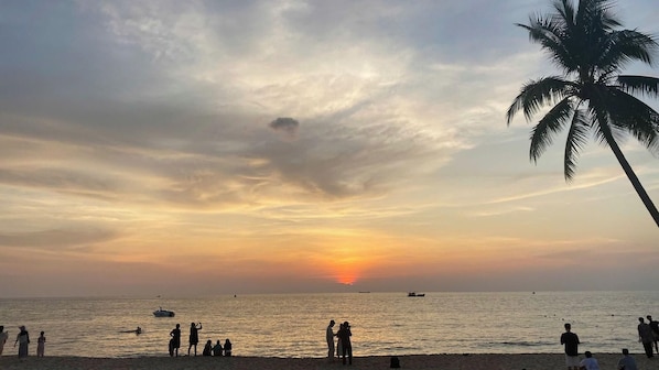 A beach with people, boats, and a sunset. - Lalisa Hotel (Phu Quoc)