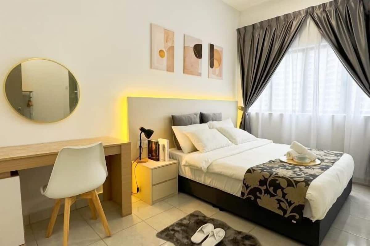 A hotel room with a bed, bedside table, chair, and a desk.