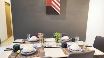 A dining table set with plates, bowls, chopsticks, and a vase with flowers.