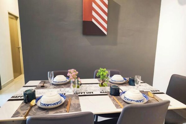 Una mesa de comedor dispuesta con platos, tazones, palillos y un florero con flores.
