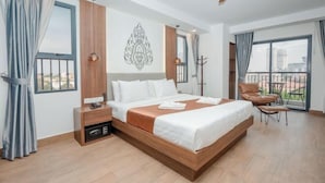 Ett modernt hotellrum med en stor säng, ett skrivbord, en stol och en balkong med utsikt.