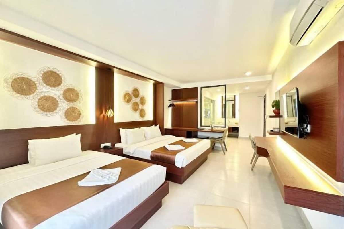 A hotel room with two beds, a desk, and a mirror.