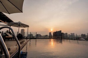 A rooftop pool with a city skyline in the background during sunset. - Botum Domrey Hotel (Phnom Penh)