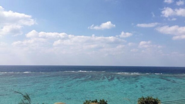Une vue sur la côte, avec une eau turquoise limpide et un ciel partiellement nuageux.