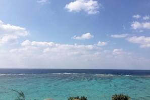 A coastal view with clear turquoise waters and a partly cloudy sky. - Lilac (Onna)