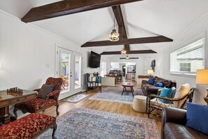 A spacious living room with a wooden ceiling, a fireplace, and a large window. - POOL HOT TUB! Entertainment & Location- Something for Everyone! (Long Beach)