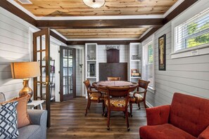 A dining area with a round wooden table and chairs, a red sofa, and a lamp. - POOL HOT TUB! Entertainment & Location- Something for Everyone! (Long Beach)