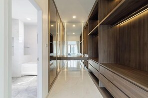 Un pasillo moderno con un banco de madera, un separador de vidrio y una habitación blanca al fondo.