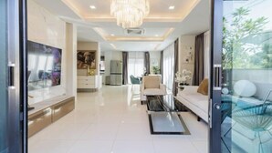 A modern living room with a chandelier, a sofa, a coffee table, and a TV. - Pattaya detached four-bedroom five-bed room pool villa (Pattaya)