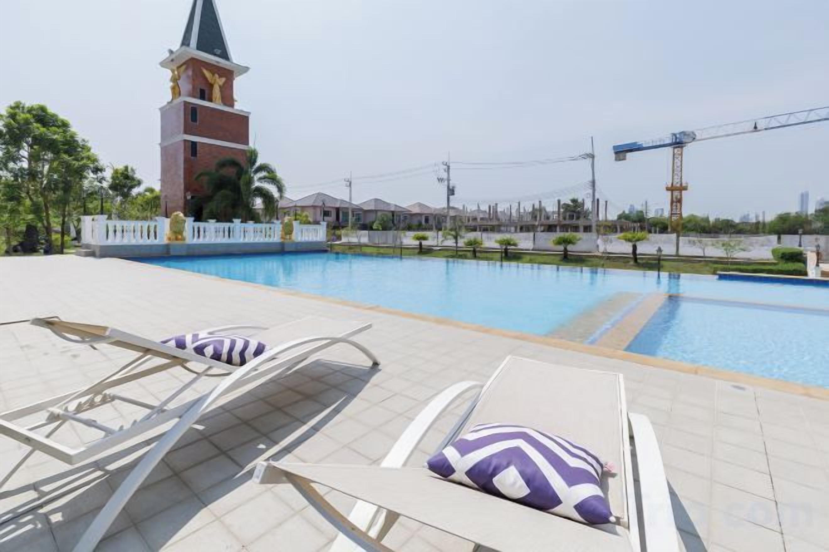 A swimming pool with lounge chairs and a tower in the background.
