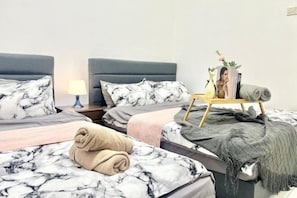 A hotel room with two beds, a bedside table, a lamp, a small table with a photo frame, and a rolled towel on one bed. - Puchong SkyPod Residence 1-10pax next to IOI Mall Wi-Fi MRT (Puchong)
