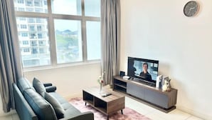 A living room with a sofa, TV, and a window with curtains. - Puchong SkyPod Residence 1-10pax next to IOI Mall Wi-Fi MRT (Puchong)