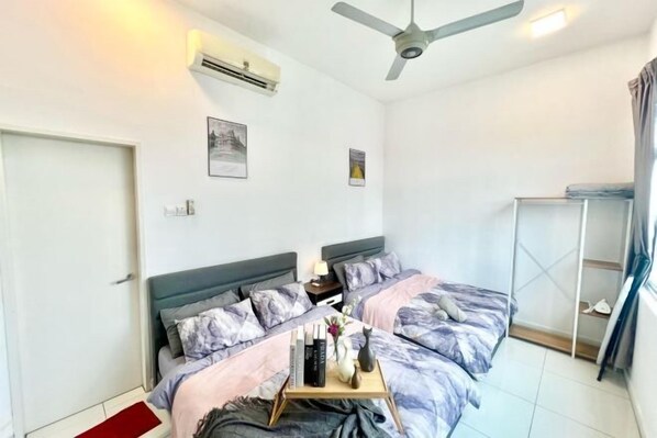 A bedroom with two beds, a ceiling fan, an air conditioner, and a small bedside table with a lamp. - Puchong SkyPod Residence 1-10pax next to IOI Mall Wi-Fi MRT (Puchong)