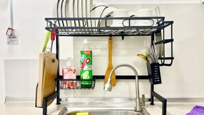 A kitchen with a metal rack holding dishes, a wooden cutting board, a bottle of dish soap, and a wooden spoon. - Puchong SkyPod Residence 1-10pax next to IOI Mall Wi-Fi MRT (Puchong)