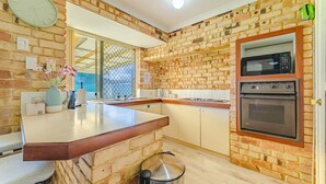 Una cocina con paredes de ladrillo, encimera de madera, horno empotrado y microondas.