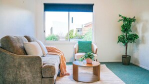 Una sala de estar con un sofá, una silla, una mesa de centro y una planta en maceta.