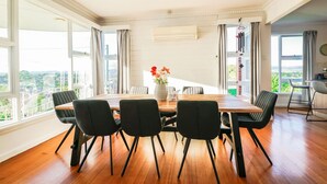 Un comedor con una mesa de madera, sillas negras y un jarrón con flores.