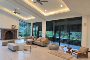 A spacious living room with a fireplace, large windows, and modern furniture. - Deco Home Mesilau Golf Bungalow @ Kundasang (Kundasang)