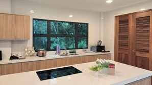 Una cocina moderna con un ventanal grande, armarios de madera, horno integrado y una encimera con varios objetos.