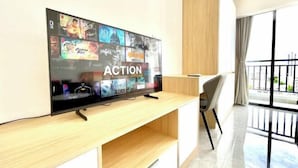 A flat-screen TV mounted on a wooden TV stand in a modern room with a balcony.
