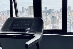 Una silla con un panel de control en una habitación con grandes ventanales con vistas a la ciudad.