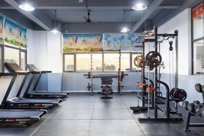 Une salle de sport équipée de tapis de course, de matériel de musculation et ornée d’une fresque murale.